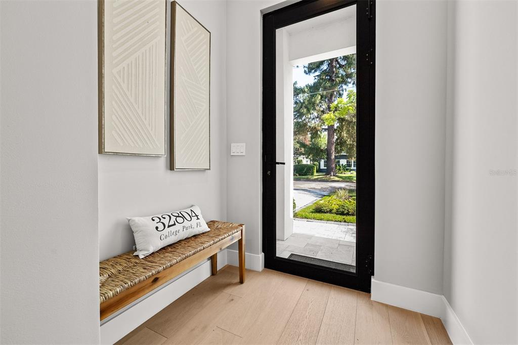 A bright entryway features a wooden bench with a decorative pillow beside a glass door — 113 W EVANS STREET, ORLANDO, FL