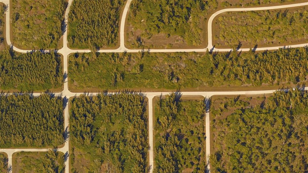An aerial view shows a grid of paved roads surrounding undeveloped, wooded residential lots — 15638 APPLETON BOULEVARD, PORT CHARLOTTE, FL