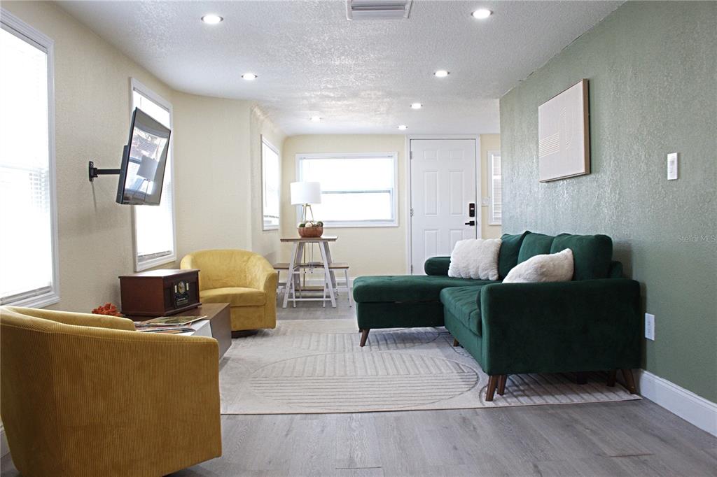 A living room features a green sectional sofa, two yellow chairs, and a small dining table — 5260 8TH AVENUE N, ST PETERSBURG, FL