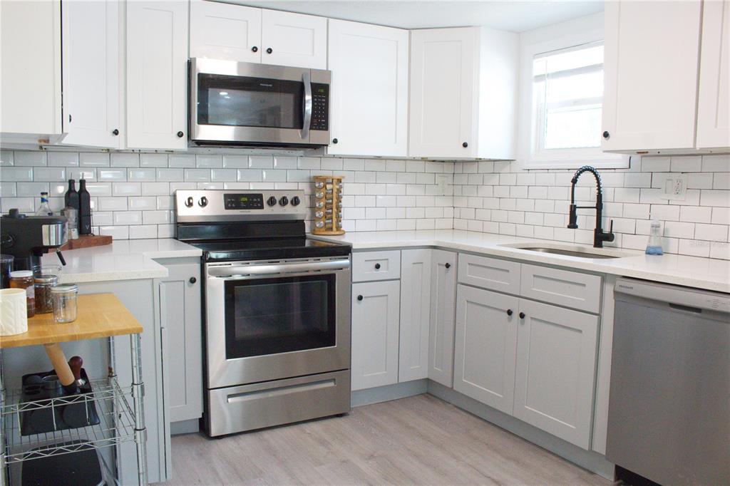 A kitchen features white cabinets, stainless steel appliances, a subway tile backsplash, and light flooring — 5260 8TH AVENUE N, ST PETERSBURG, FL