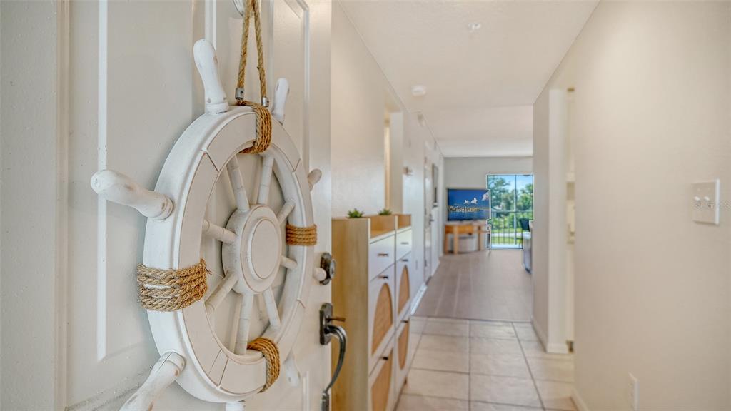 A white ship's wheel hangs on the front door, opening into a tiled hallway — 9330 CLUBSIDE CIRCLE UNIT 3202, SARASOTA, FL