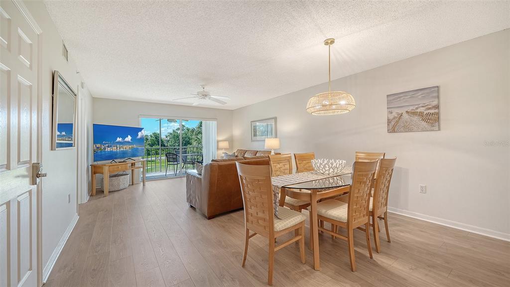 A dining area with a glass table and chairs opens into a living room with balcony — 9330 CLUBSIDE CIRCLE UNIT 3202, SARASOTA, FL