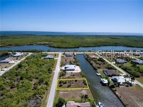 An aerial view shows a vacant rectangular lot outlined in yellow next to a canal — 15674 MARGO CIRCLE, PORT CHARLOTTE, FL