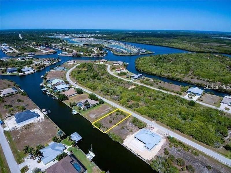 An aerial view shows a vacant waterfront lot outlined in yellow along a canal — 15674 MARGO CIRCLE, PORT CHARLOTTE, FL