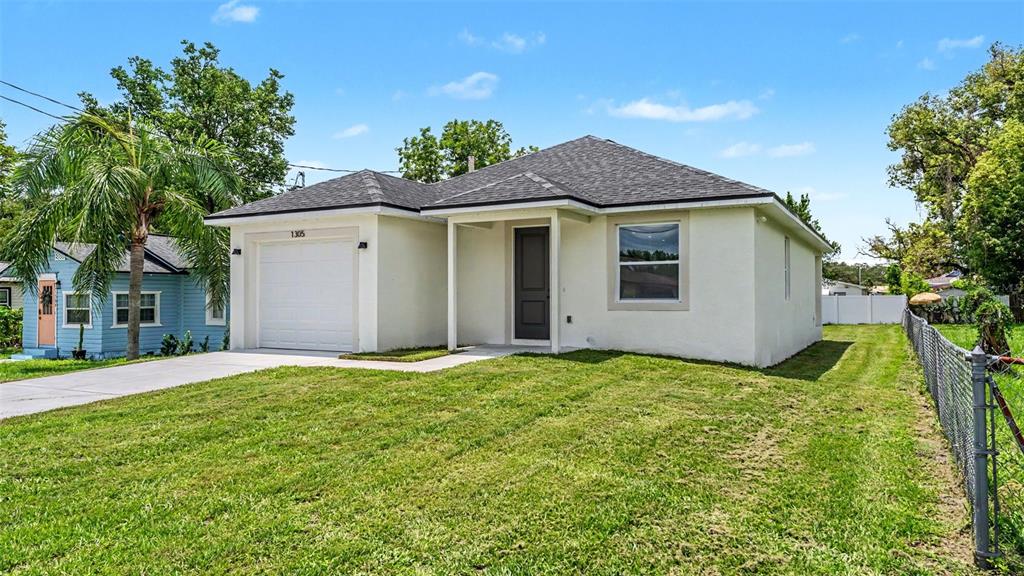 A single-story house with a white stucco exterior, a garage, and a front porch — 1305 E PARKER STREET, LAKELAND, FL