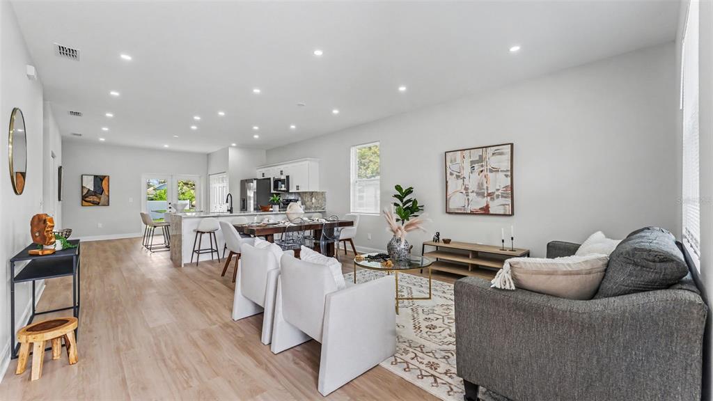 An open-concept living and dining area features light wood flooring, white walls, and recessed lighting — 1305 E PARKER STREET, LAKELAND, FL