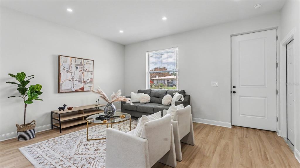A living room features light wood flooring, a gray sofa, two armchairs, and a window — 1305 E PARKER STREET, LAKELAND, FL