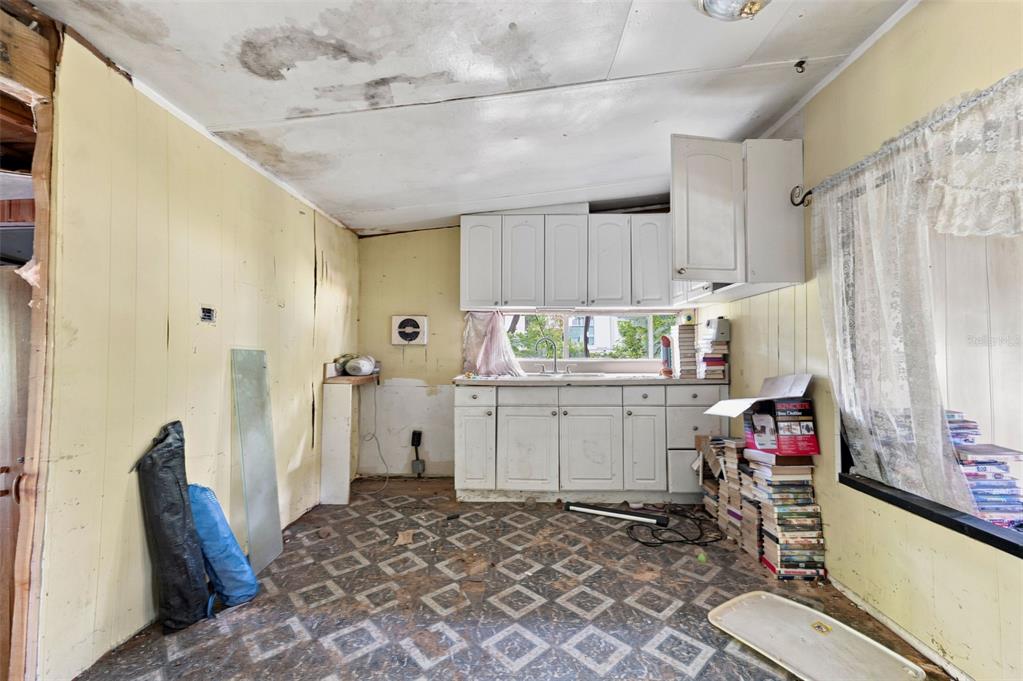 A kitchen with white cabinets, patterned flooring, and water-damaged ceiling panels — 13129 CLERMONT STREET, HUDSON, FL