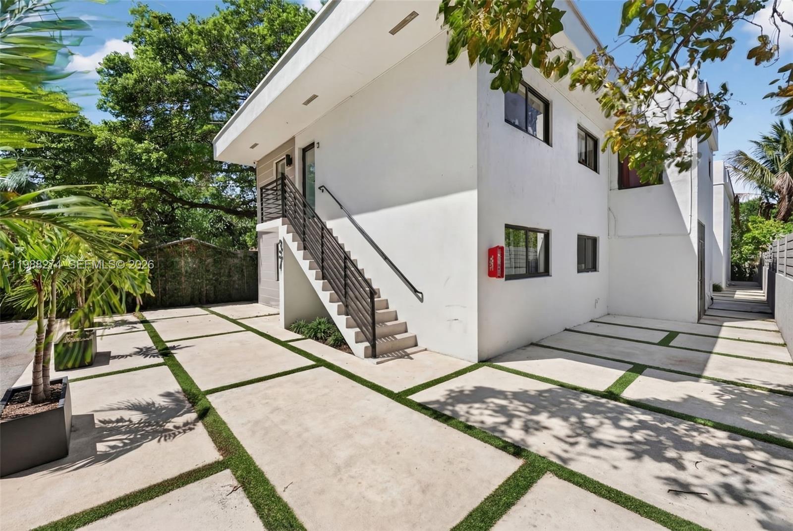 A two-story white building features an exterior staircase and a concrete paver driveway with grass — 37 NW 59th St # 4, Miami FL 33127, MIAMI, FL