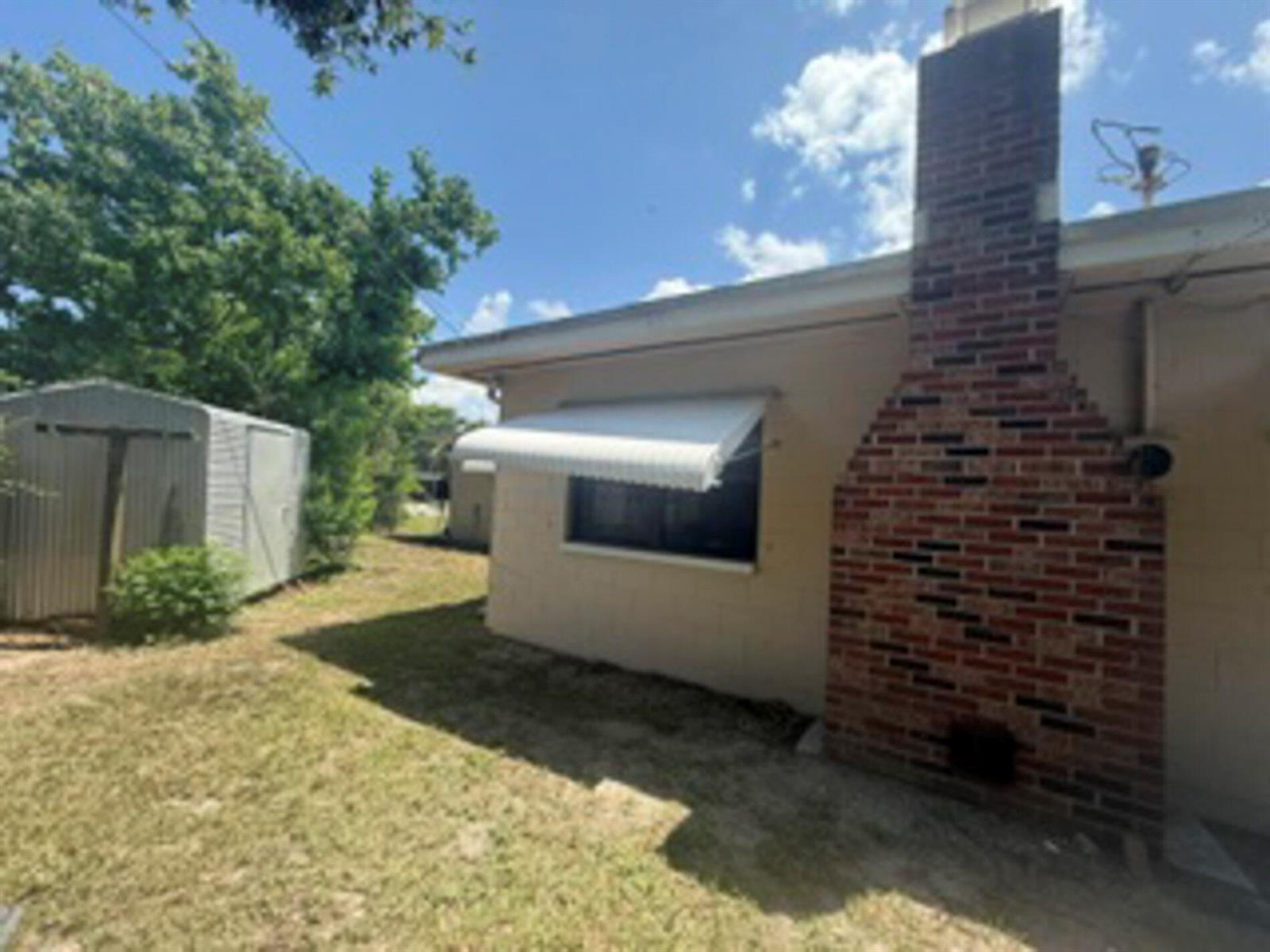 The exterior of a house features a brick chimney, a window with an awning, and siding — 1102 Greenwood Way, Cocoa FL 32922, COCOA, FL