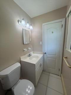 A bathroom features a white vanity, a toilet, a wall mirror, and light-colored tile flooring — 1102 Greenwood Way, Cocoa FL 32922, COCOA, FL