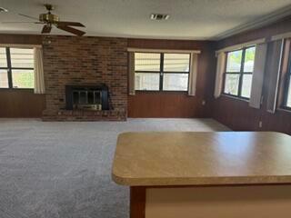 A living room features a brick fireplace, wood-paneled walls, carpeted floors, and a ceiling fan — 1102 Greenwood Way, Cocoa FL 32922, COCOA, FL