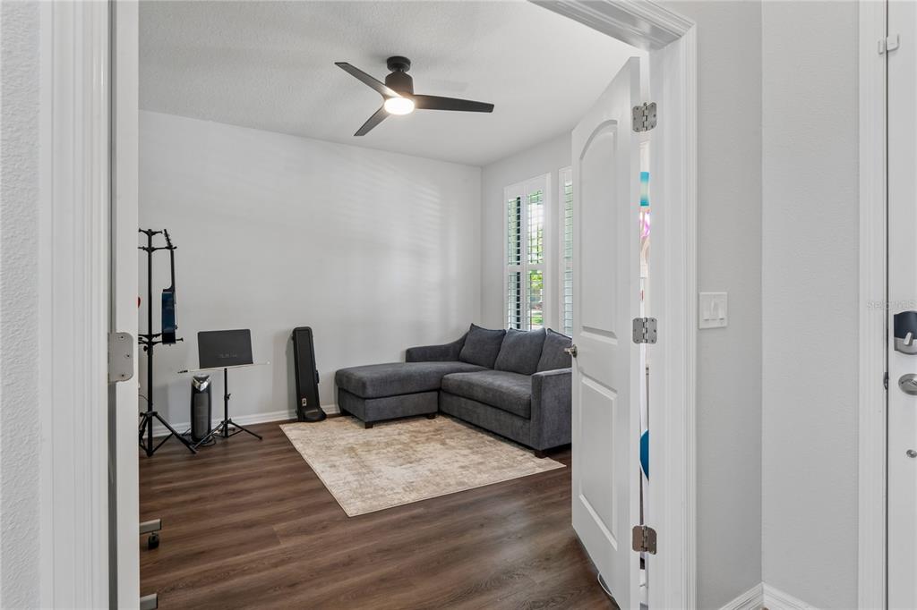 A room with wood-look flooring, a gray sectional sofa, and a ceiling fan — 12299 LAKE BLANCHE DRIVE, ODESSA, FL
