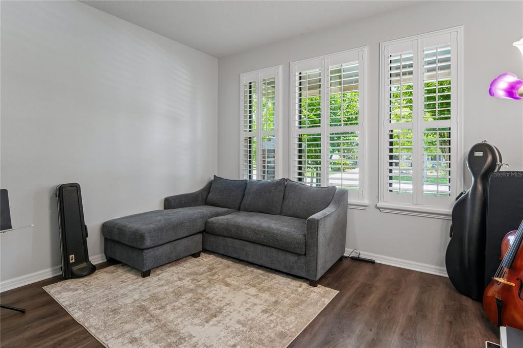 A gray sectional sofa sits on a rug in a room with white plantation shutters — 12299 LAKE BLANCHE DRIVE, ODESSA, FL