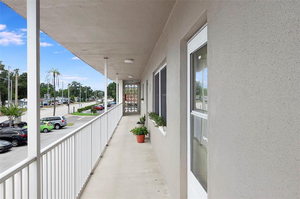 An outdoor apartment balcony features a white metal railing, concrete flooring, and a screen door — 1225 58TH STREET N UNIT 203A, ST PETERSBURG, FL
