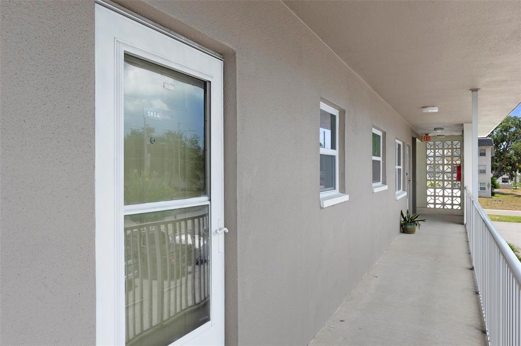 An exterior walkway with a white door, windows, and a metal railing — 1225 58TH STREET N UNIT 203A, ST PETERSBURG, FL