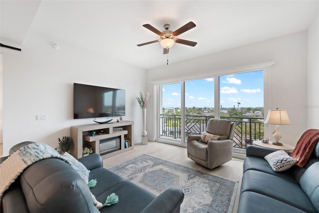 A living room features two leather sofas, a television, a ceiling fan, and a balcony — 300 150TH AVENUE UNIT 510, MADEIRA BEACH, FL