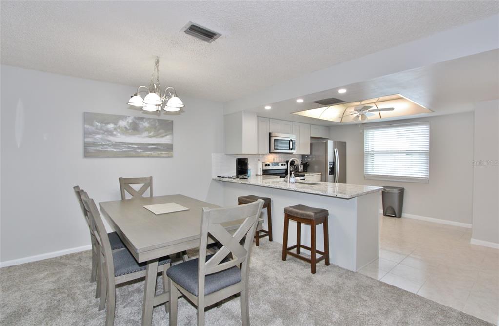 A dining area with a table and chairs adjacent to a kitchen with granite countertops — 9635 GREENSKEEPER DRIVE, NEW PORT RICHEY, FL
