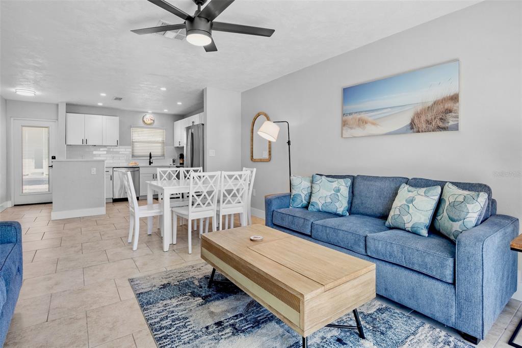A living room with a blue sofa and a dining area with white furniture — 5830 MIDNIGHT PASS ROAD UNIT 93, SARASOTA, FL