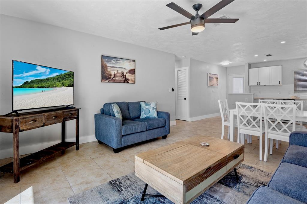 A living room features a blue sofa, a wooden coffee table, and a dining area — 5830 MIDNIGHT PASS ROAD UNIT 93, SARASOTA, FL