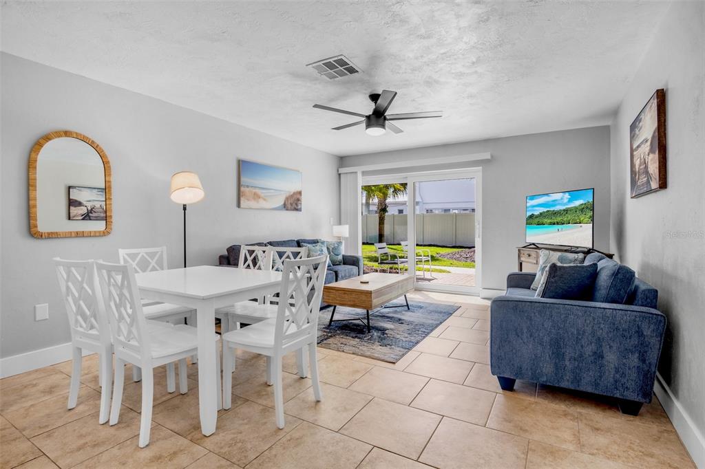 A living and dining area features tile flooring, white furniture, and a sliding glass door — 5830 MIDNIGHT PASS ROAD UNIT 93, SARASOTA, FL