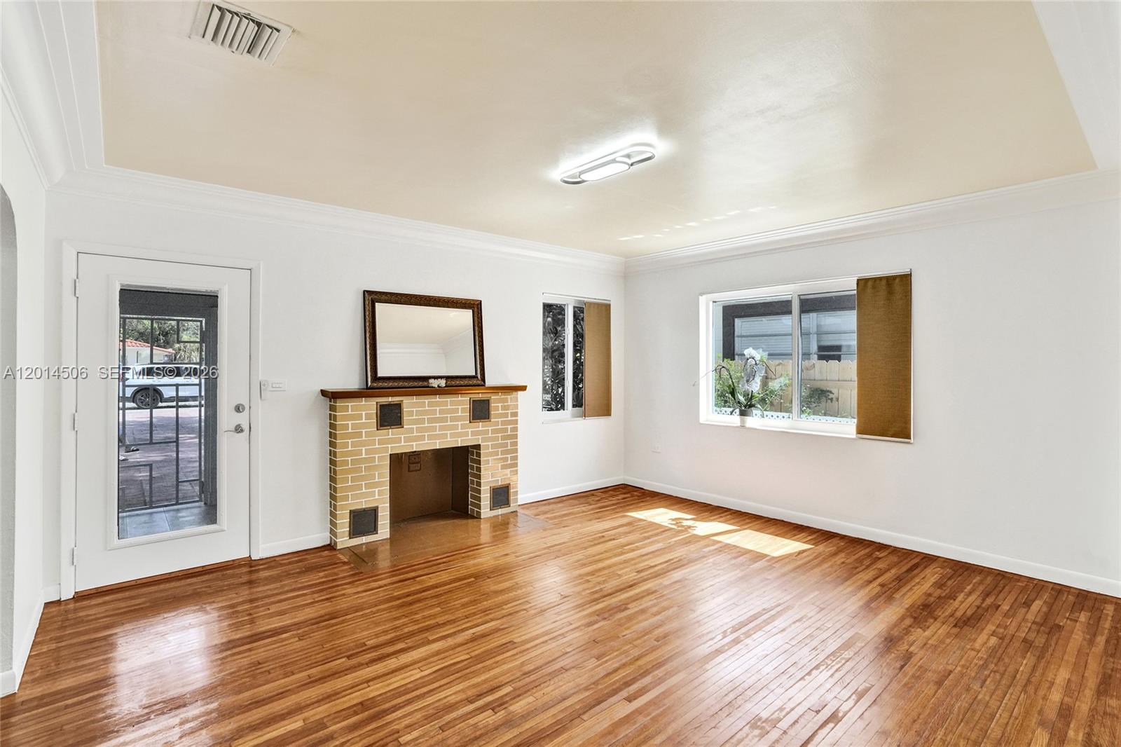 A living room features a brick fireplace, hardwood floors, and a glass-paneled exterior door — 2420 SW 16th St, Miami FL 33145, MIAMI, FL