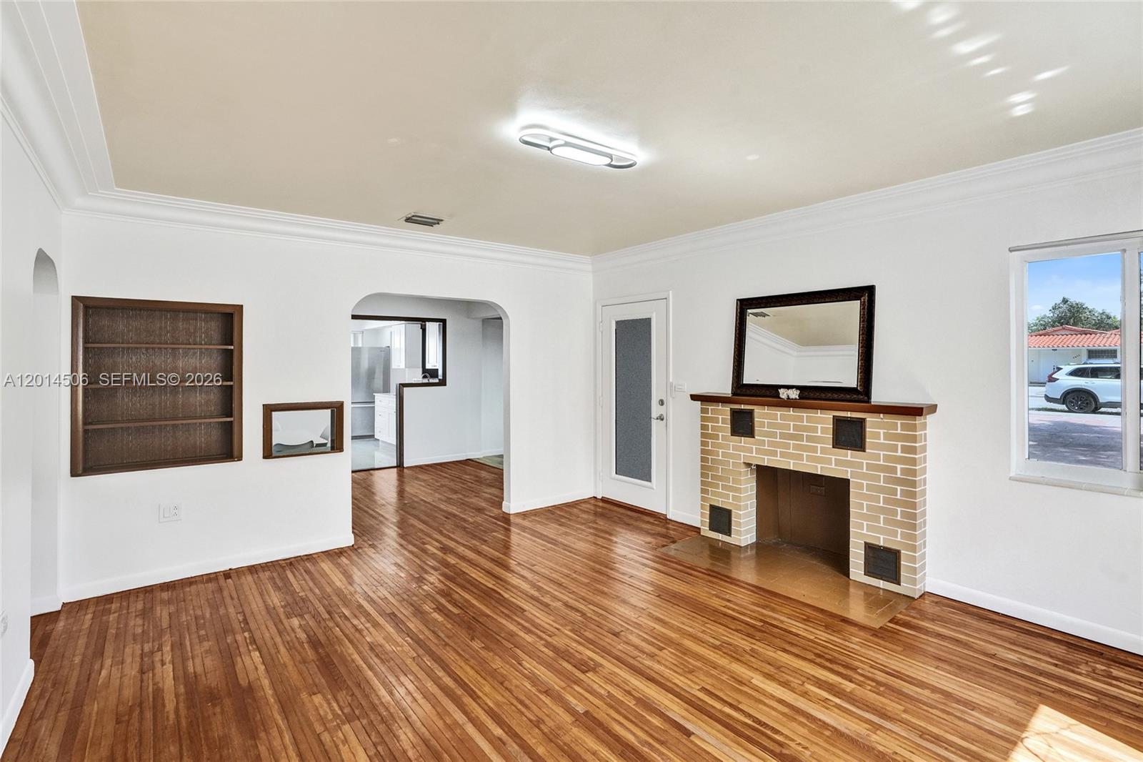 A living room features hardwood floors, a brick fireplace, and an arched doorway to the kitchen — 2420 SW 16th St, Miami FL 33145, MIAMI, FL