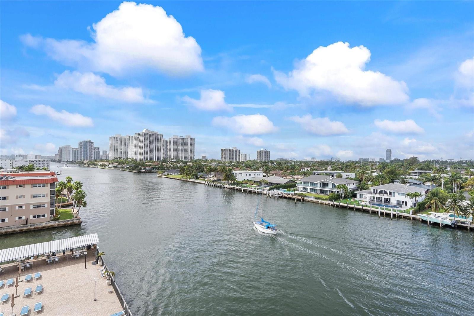 An elevated view of a waterway with a sailboat, waterfront homes, and distant high-rise buildings — 2017 S Ocean Drive # 710, Hallandale Beach FL 33009, HALLANDALE BEACH, FL