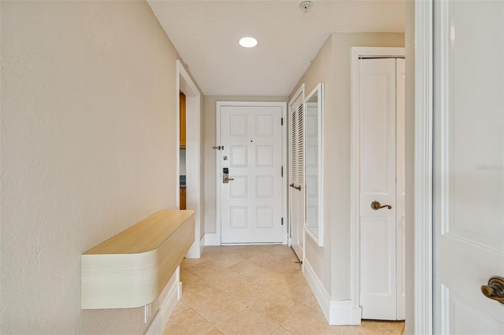 An entryway features a light wood floating shelf, tiled floors, and a white front door — 36750 US 19 N UNIT 22207, PALM HARBOR, FL