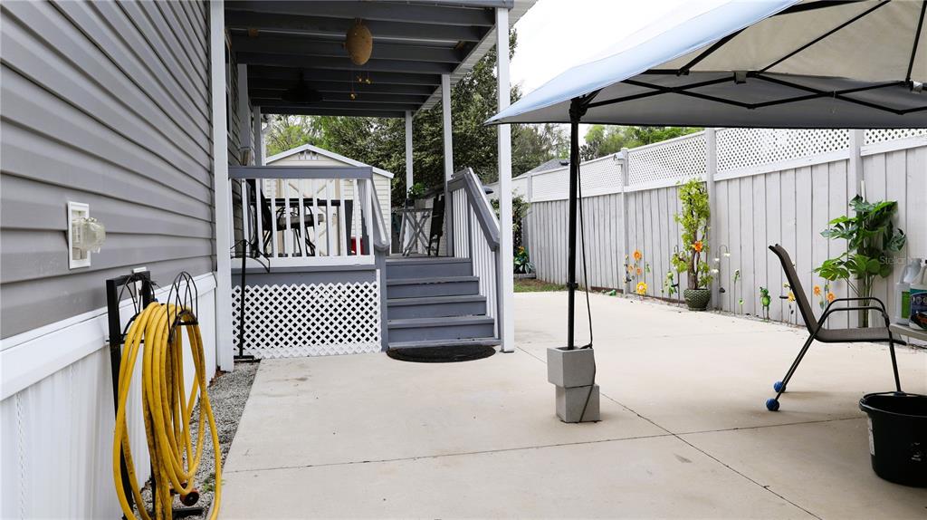 A concrete patio features a covered porch with stairs, a yellow hose, and a canopy — 1912 CR 439C, LAKE PANASOFFKEE, FL