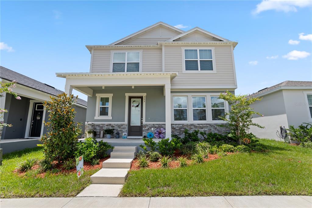 A two-story house with light gray siding, a stone facade, and a covered front porch — 353 FREE RANGE DRIVE, GROVELAND, FL