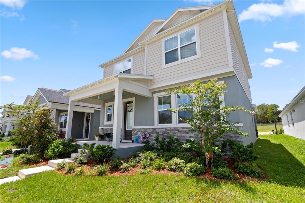 A two-story house with beige siding, gray stucco, and a stone veneer front porch — 353 FREE RANGE DRIVE, GROVELAND, FL