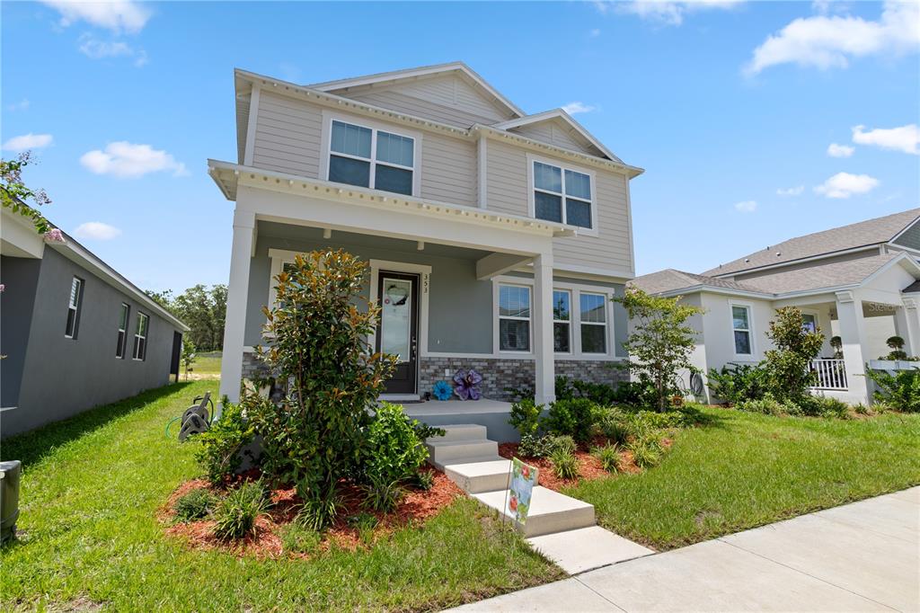 A two-story suburban house with light gray siding, a front porch, and a stone facade — 353 FREE RANGE DRIVE, GROVELAND, FL