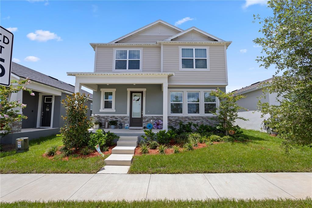 A two-story house with light gray siding, a stone facade, and a front porch — 353 FREE RANGE DRIVE, GROVELAND, FL