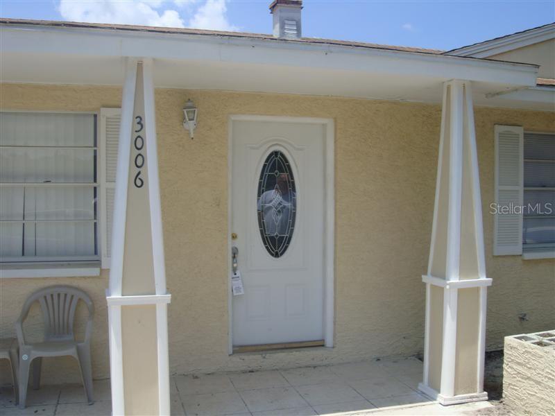 A beige house exterior features a white front door with an oval glass insert — 3006 N 44TH STREET, TAMPA, FL