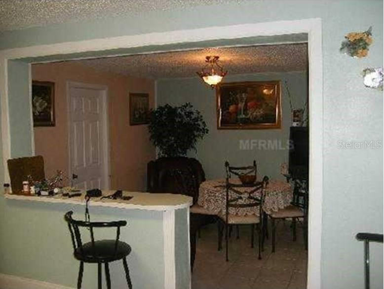 A dining area with a round table and chairs is viewed through a kitchen pass-through window — 3006 N 44TH STREET, TAMPA, FL