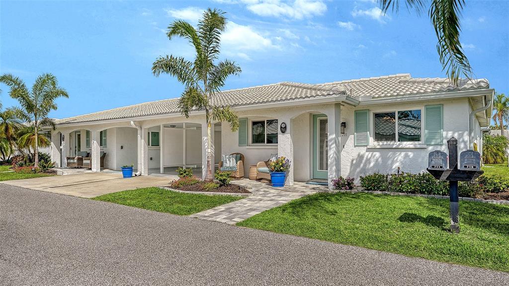 A single-story white stucco villa with a tiled roof, covered entryway, and palm trees — 711 SPANISH DRIVE S, LONGBOAT KEY, FL