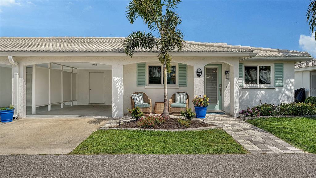 A single-story house exterior features a carport, a front patio with two chairs, and landscaping — 711 SPANISH DRIVE S, LONGBOAT KEY, FL