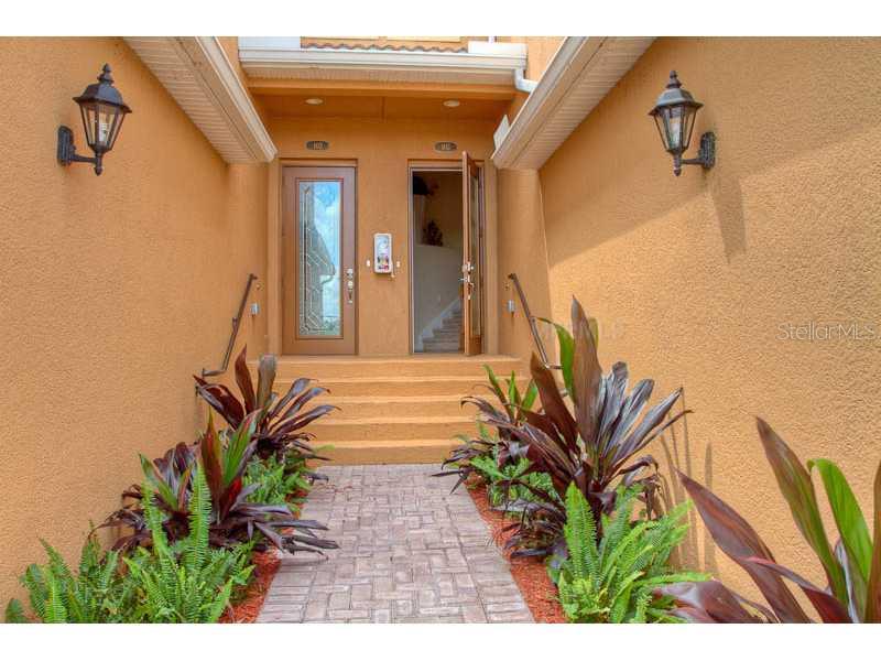 A brick walkway leads to two front doors with exterior wall lamps and tropical landscaping — 7312 RIVER HAMMOCK DRIVE UNIT 103, BRADENTON, FL