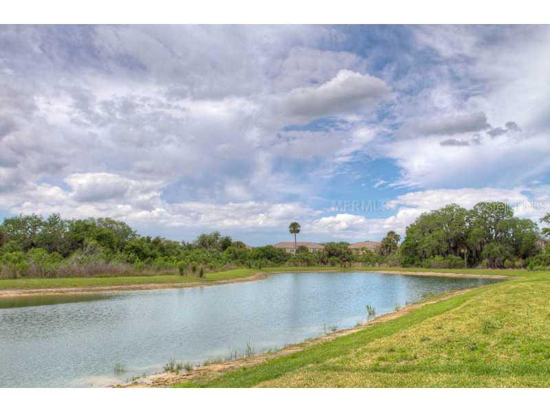 A pond surrounded by green grass and trees under a cloudy sky — 7312 RIVER HAMMOCK DRIVE UNIT 103, BRADENTON, FL