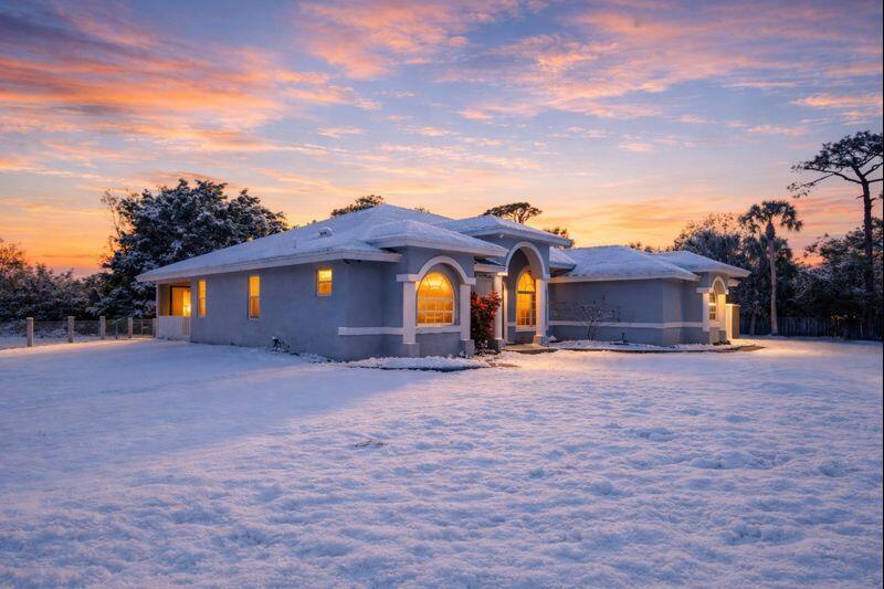 A single-story house with a gray exterior and white trim sits on a snow-covered lawn — 4584 Windmill Road, FL 33470, FL