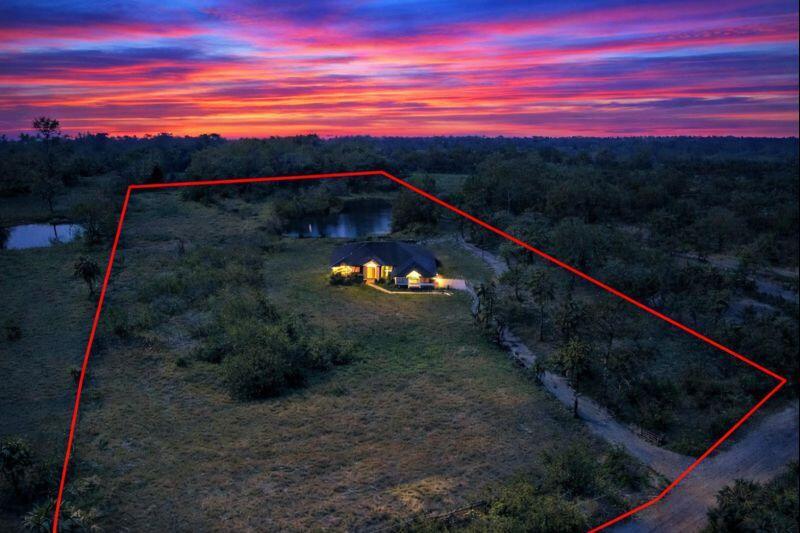 An aerial view shows a house with illuminated windows situated on a large, grassy lot — 4584 Windmill Road, FL 33470, FL