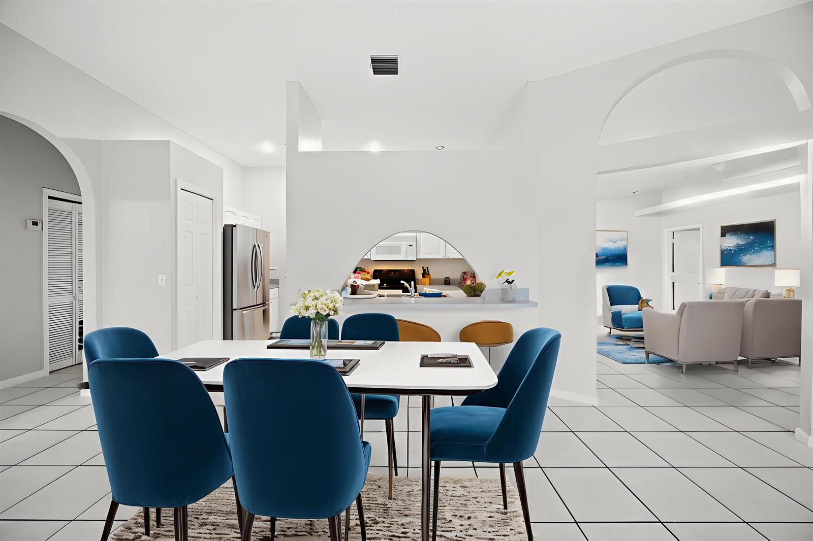 A dining area with blue chairs and a white table opens to a kitchen pass-through — 4584 Windmill Road, FL 33470, FL