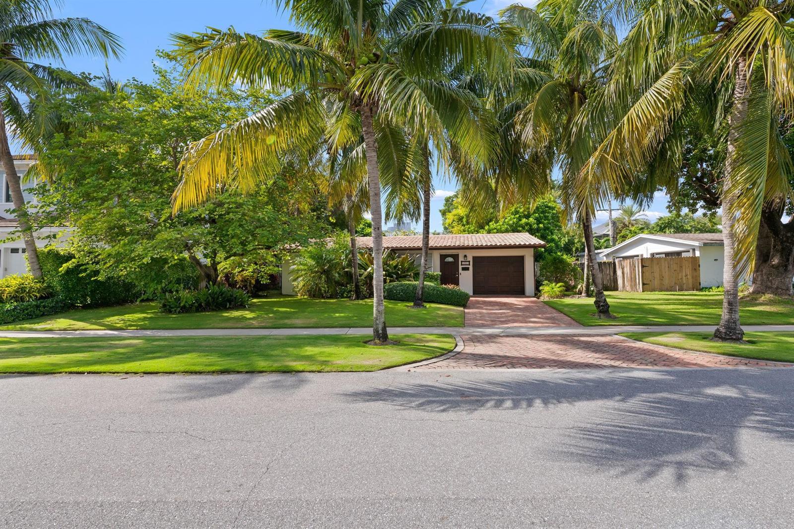 A single-story house with a brown garage and palm trees sits behind a brick driveway — 1001 NE 2nd Terrace, Boca Raton FL 33432, BOCA RATON, FL