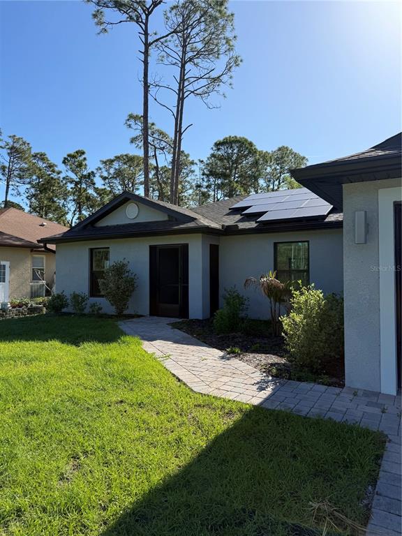 A single-story house with a paved walkway, solar panels, and a front entrance — 5436 N CHAMBERLAIN BOULEVARD, NORTH PORT, FL