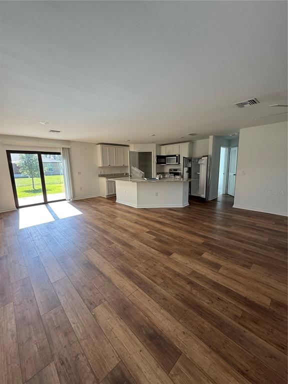 An open-concept kitchen with white cabinets and a center island overlooks a living area — 5436 N CHAMBERLAIN BOULEVARD, NORTH PORT, FL