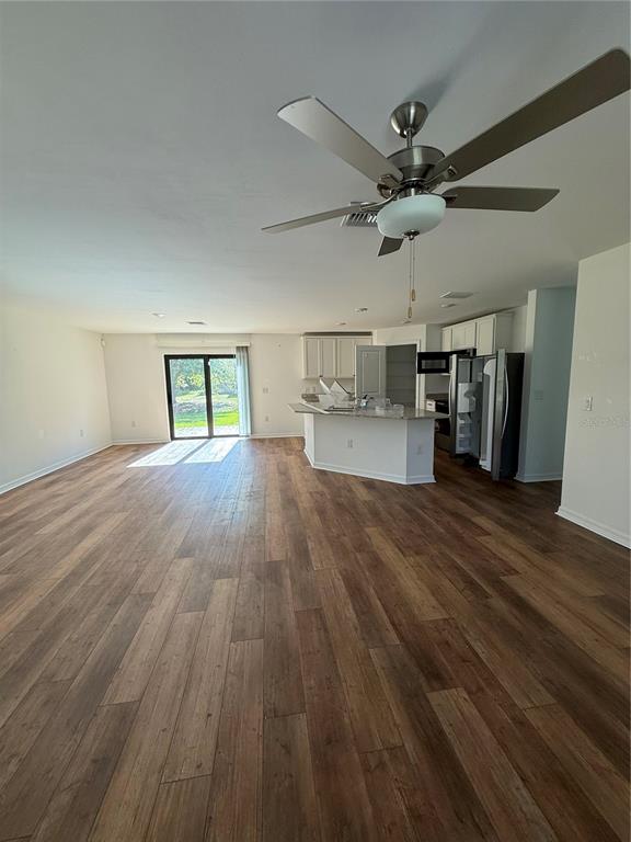 An open-concept kitchen and living area features wood-look flooring and a ceiling fan — 5436 N CHAMBERLAIN BOULEVARD, NORTH PORT, FL