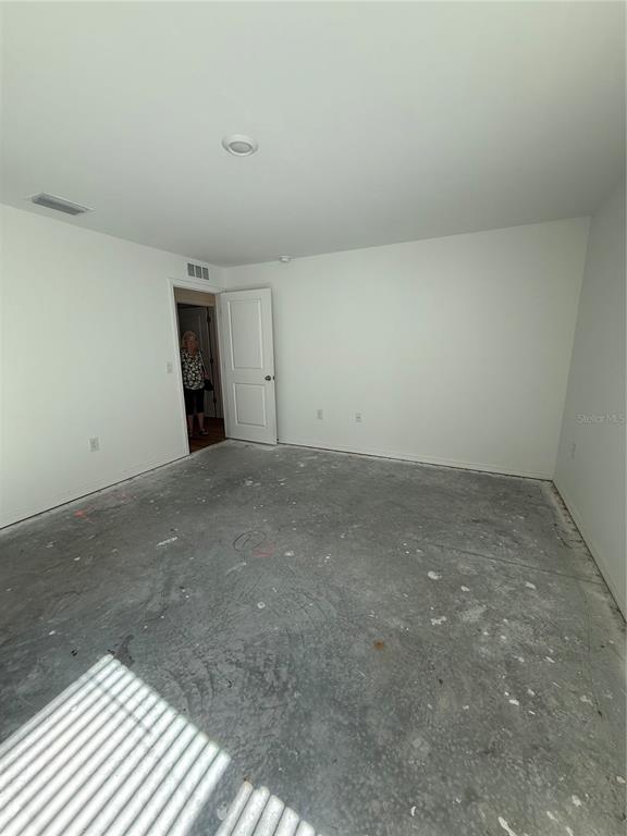 An unfinished room with white walls, a white door, and a bare concrete floor — 5436 N CHAMBERLAIN BOULEVARD, NORTH PORT, FL