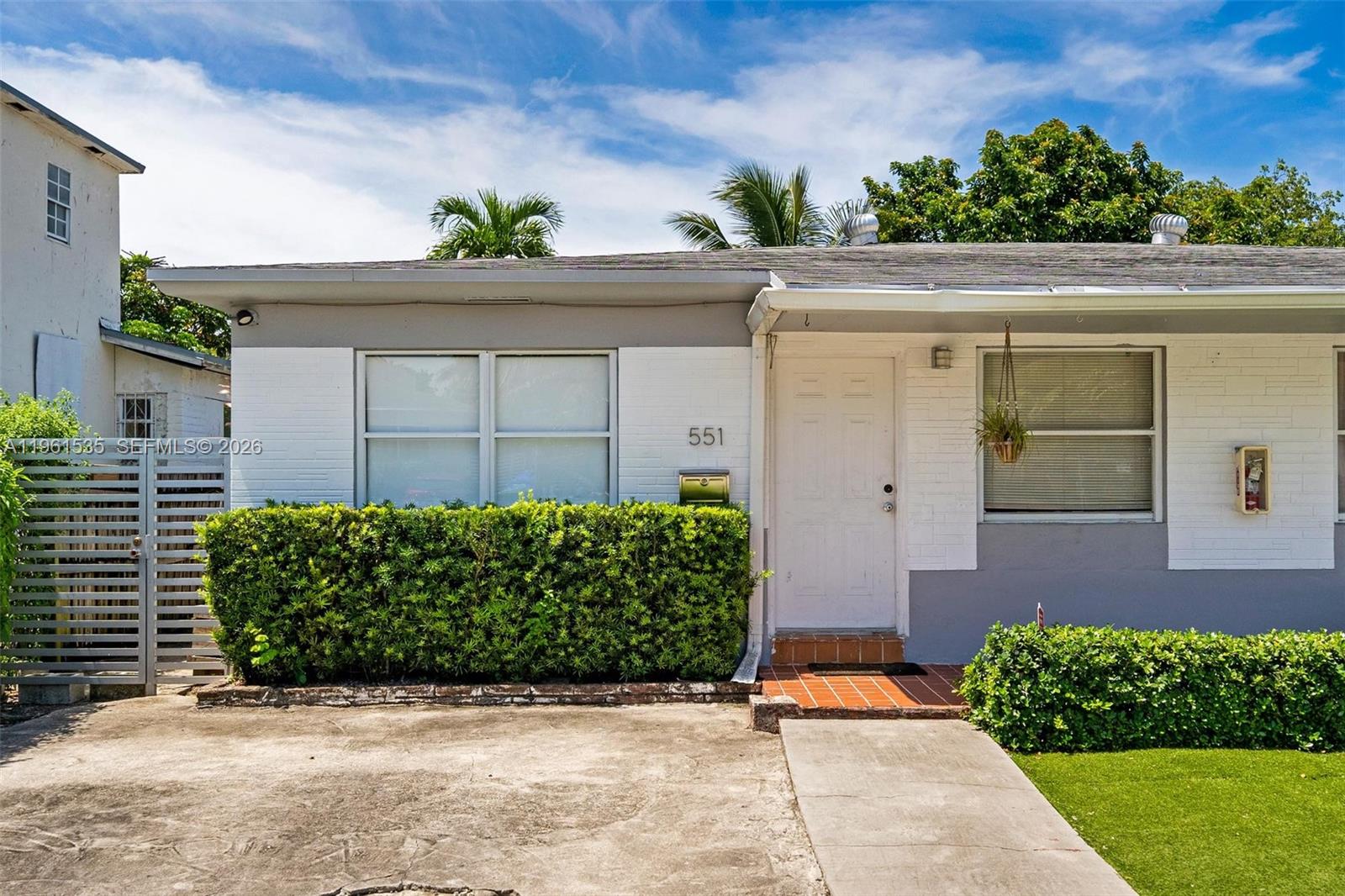 A single-story house with a white brick facade, a front door, and a paved driveway — 551 NE 67th St, Miami FL 33138, MIAMI, FL