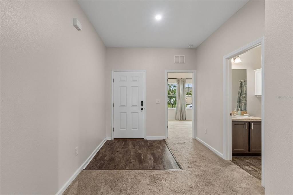 An entryway features a wood-look floor transition, beige carpet, a white door, and a bathroom — 1261 ANCHOR BEND DRIVE, RUSKIN, FL